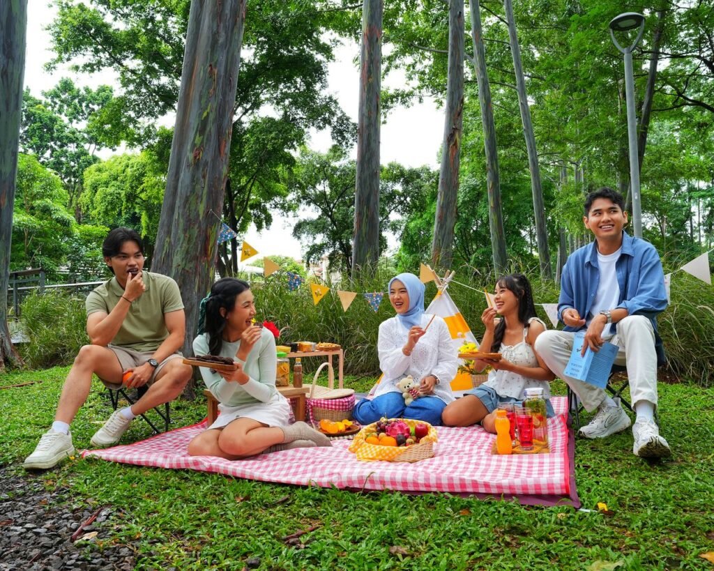 Group of friends enjoying a colorful picnic in a lush Jakarta park, sharing food and laughter.